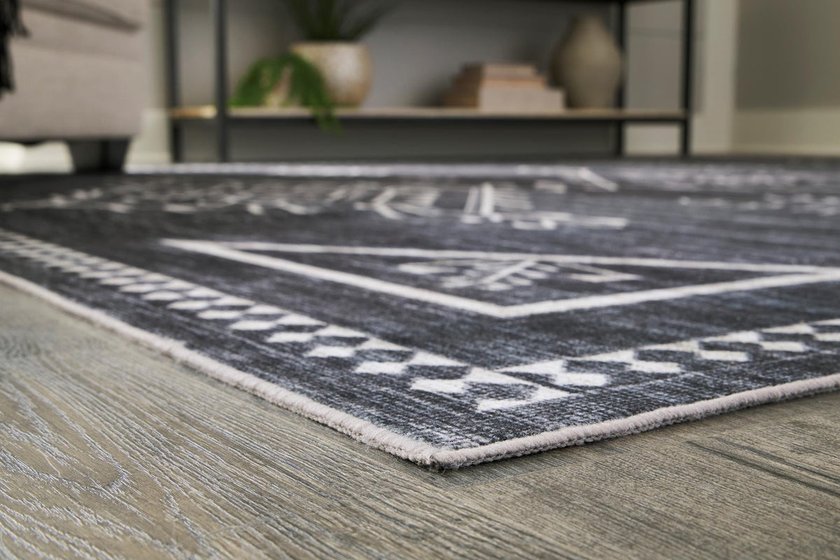 Dark gray rug with white geometric lines, corner angle view, and flatwoven texture