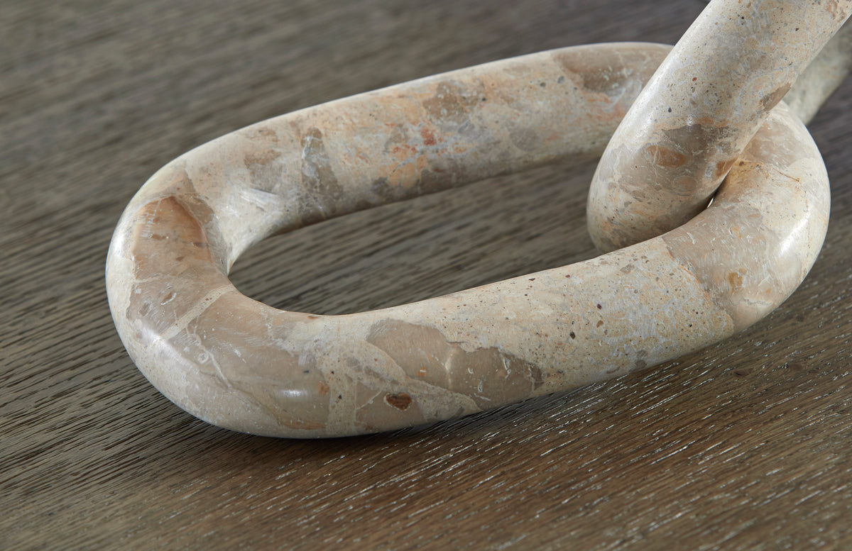 Interlocking chain-link sculpture with speckled light stone texture, close-up