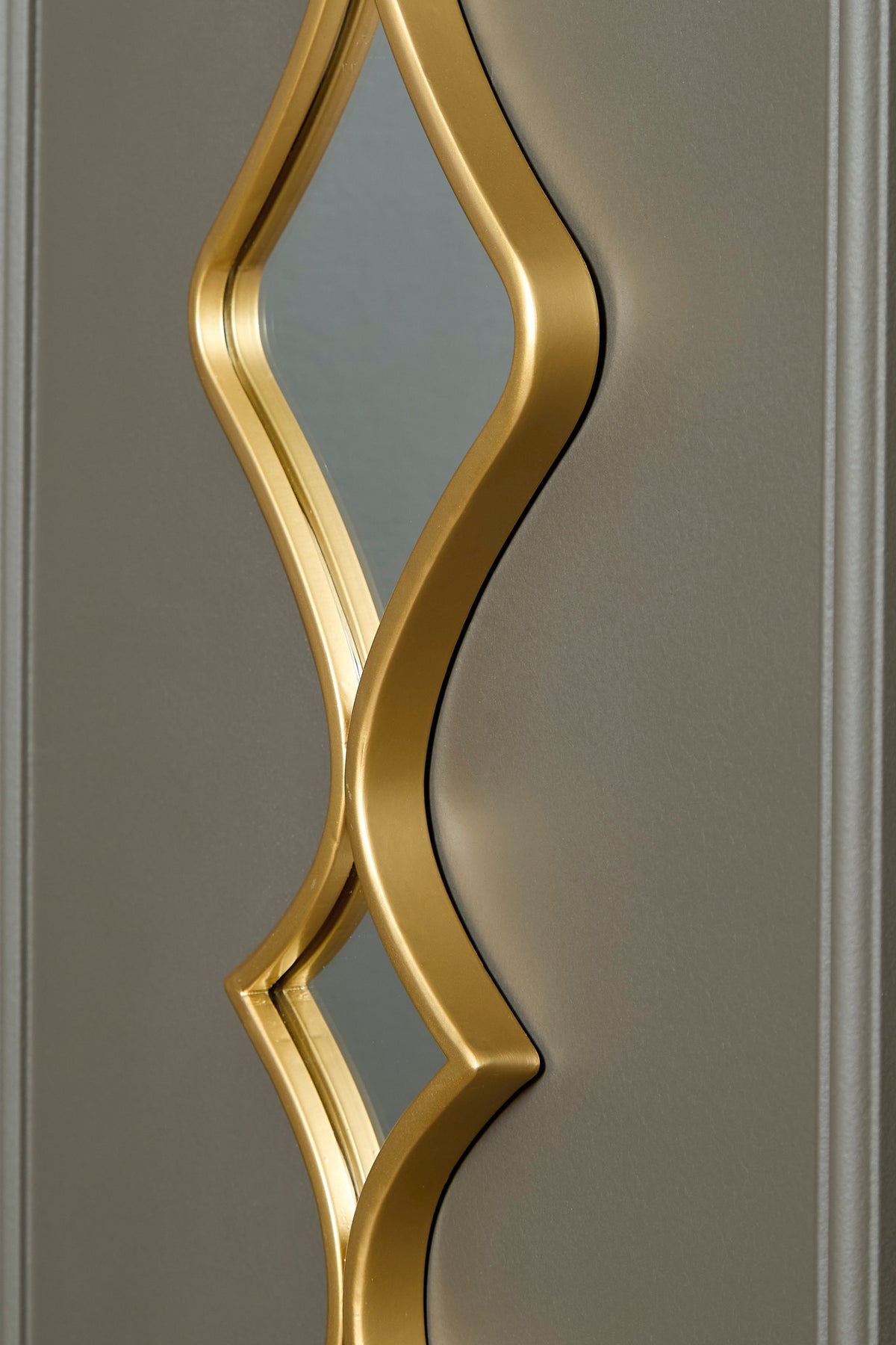 Accent mirror with gold geometric frame featuring an arched, layered cutout design