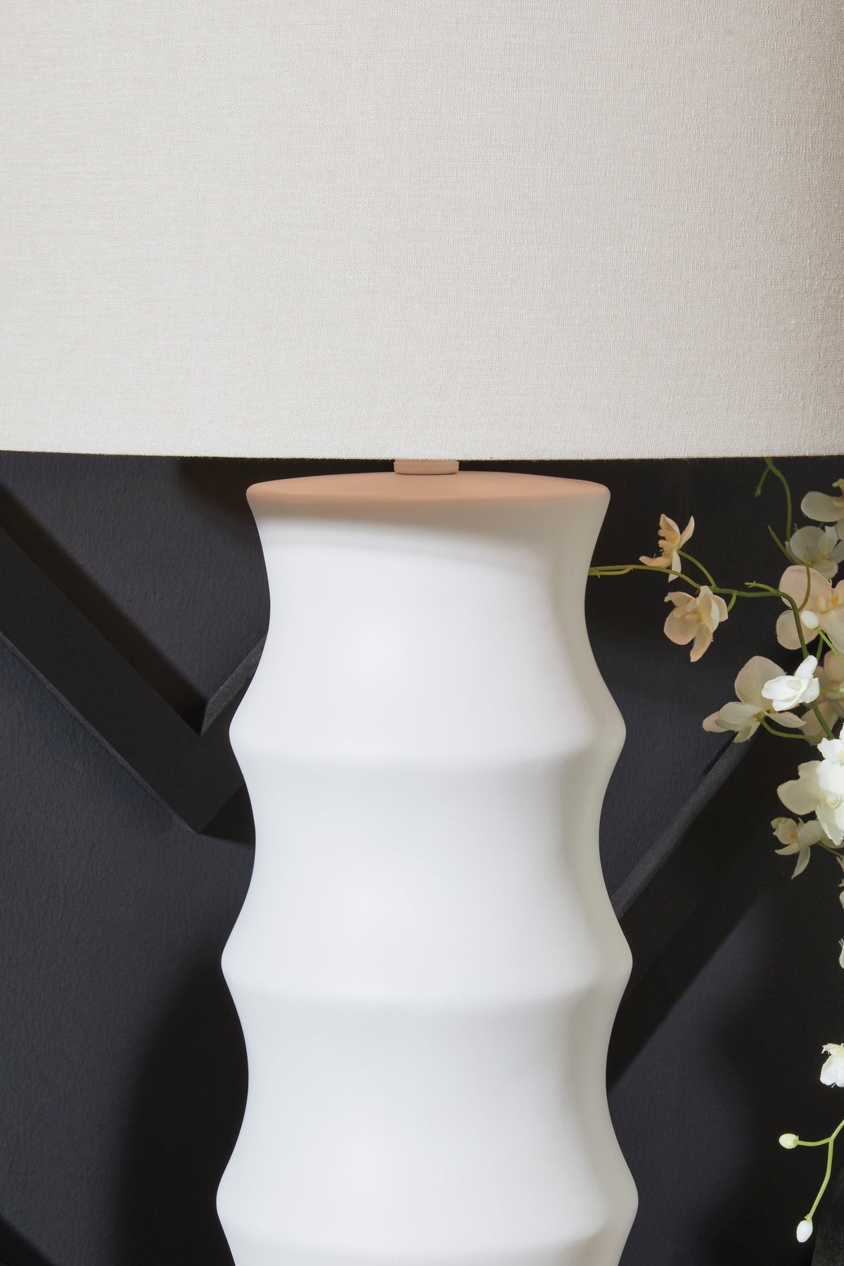 White ribbed ceramic table lamp with beige fabric drum shade, close-up