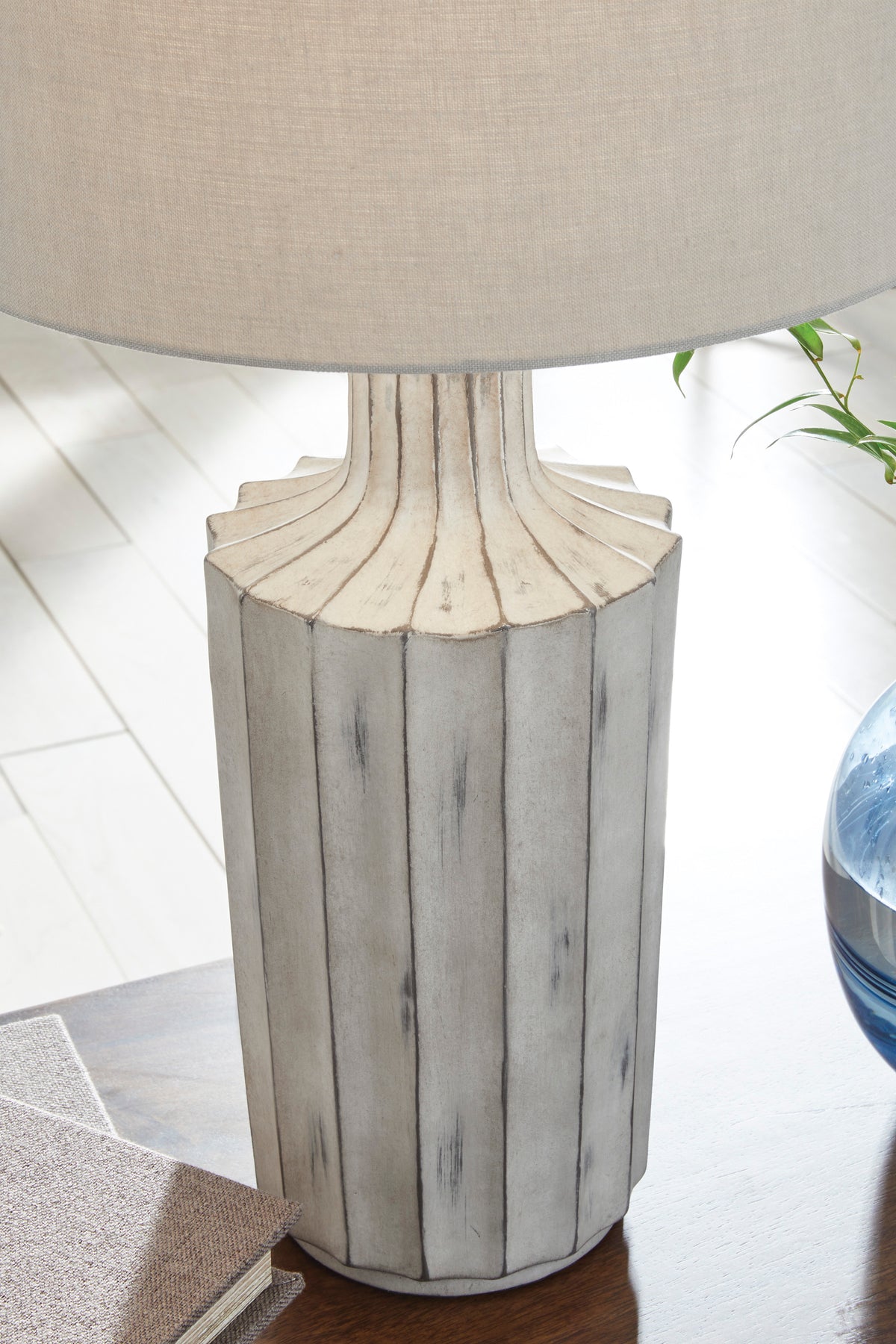 Table lamp close-up: beige drum shade on fluted gray ceramic pedestal base