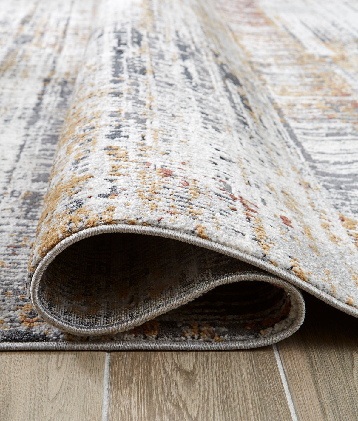 Rug edge detail with gray binding and underside visible; distressed light gray with orange tones