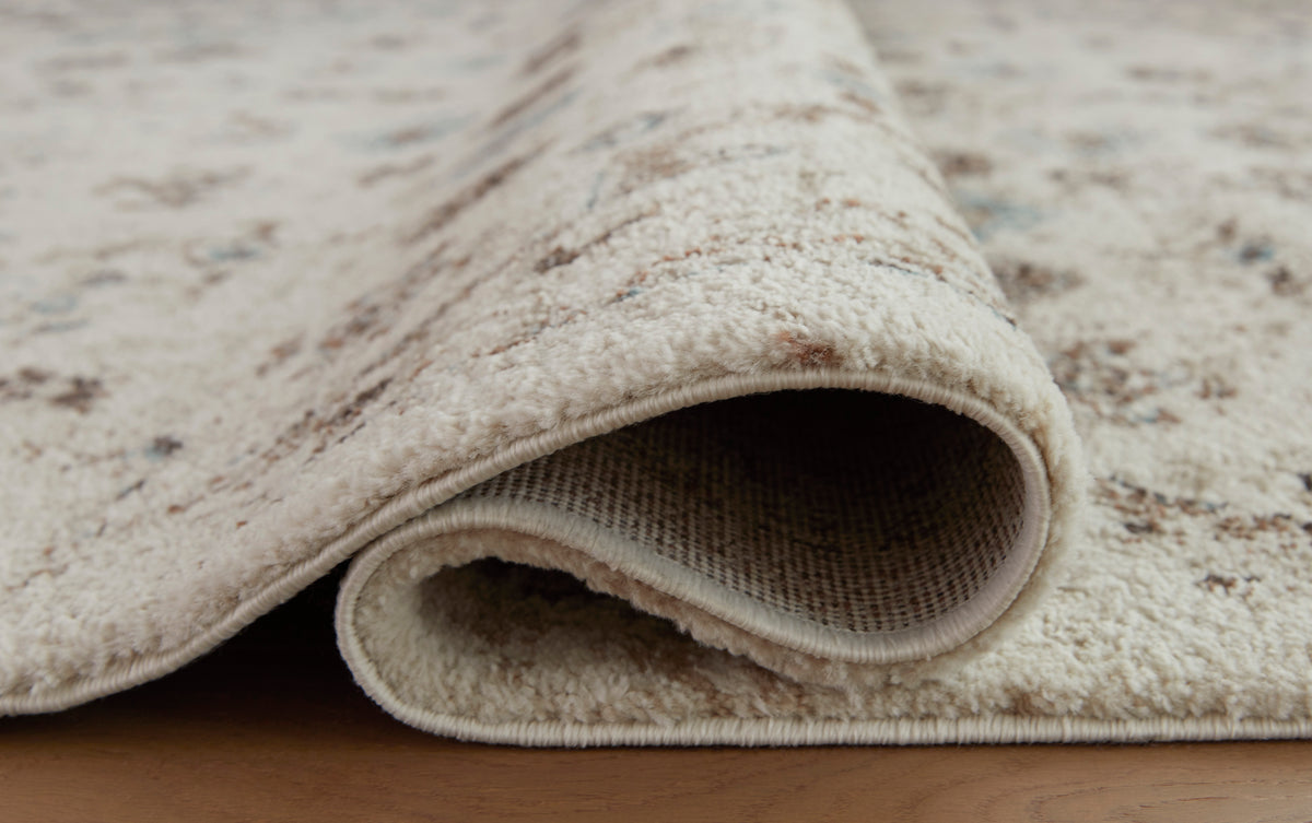 Cream rug with distressed motif and low pile, rolled edge visible