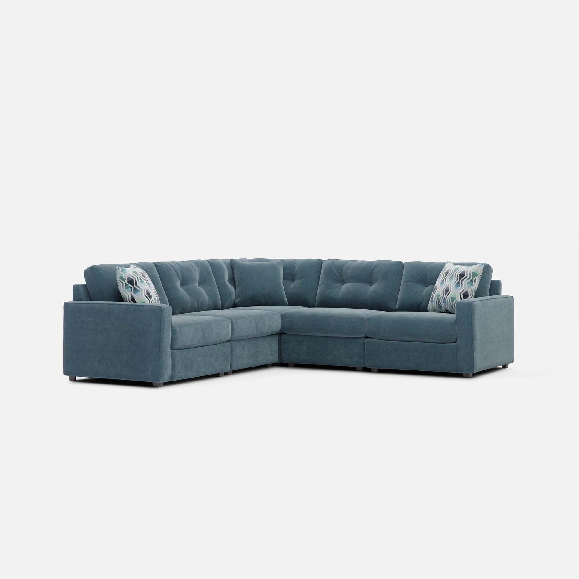 Teal modular sectional sofa with two patterned throw pillows on the back.