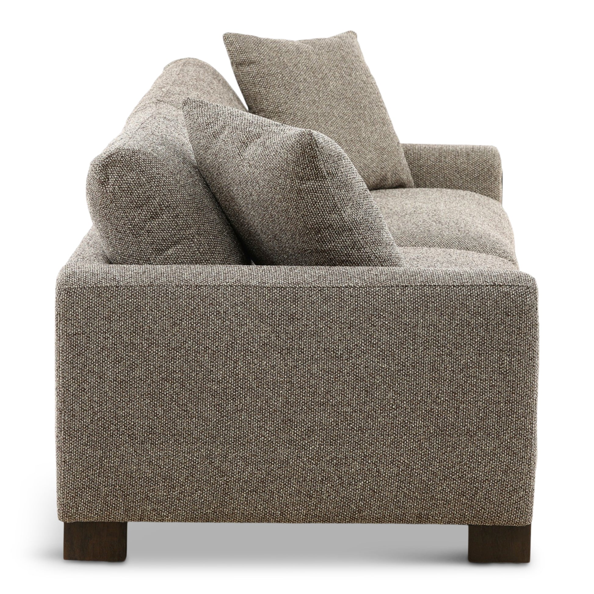 Gray fabric sofa backrest with three tall throw pillows and textured upholstery.