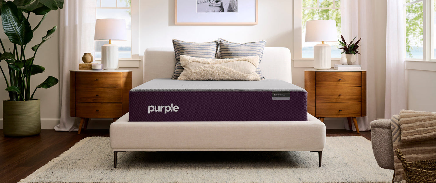 Purple mattress on a bed in a well-lit bedroom with decor elements.