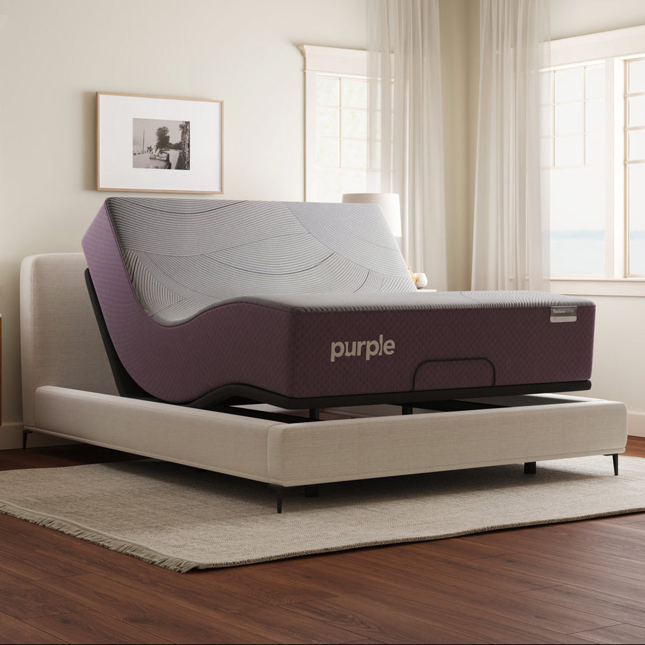 Purple adjustable bed in a room with wooden flooring and white walls.