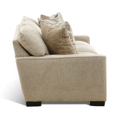 Beige sofa with rounded arms, low black feet, and layered pillows in neutral tones