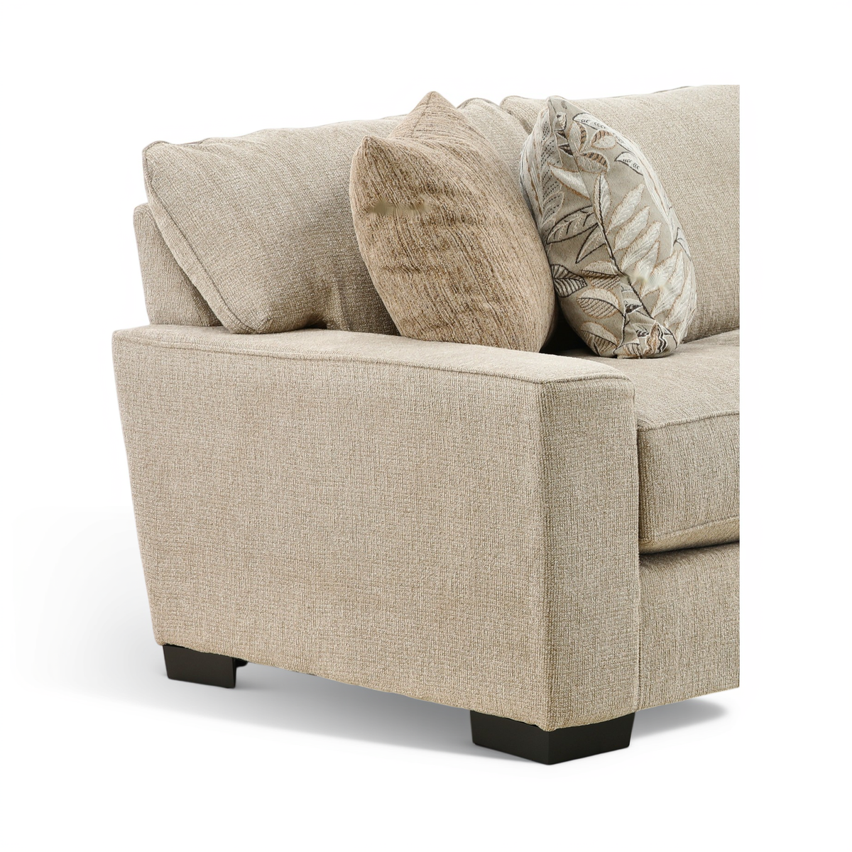 Beige sofa arm and seat detail with textured upholstery and patterned throw pillows