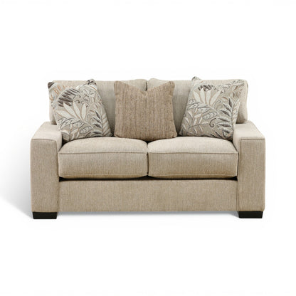 Troy loveseat in light beige fabric with two patterned accent pillows and rounded arms