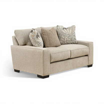 Light beige two-seat loveseat with three back cushions and two leaf-print throw pillows