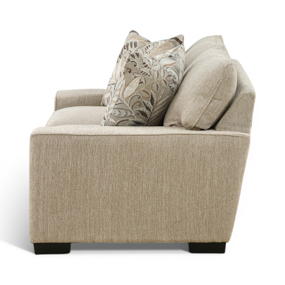 Light beige loveseat corner view with two leaf-pattern pillows and curved rolled arms