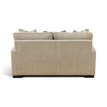 Light beige loveseat rear view with back cushion seams and stacked accent pillows