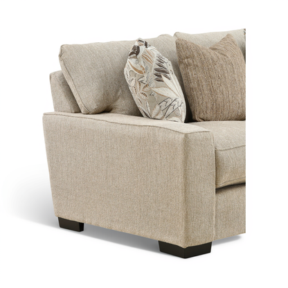 Light beige loveseat arm and seat detail with leaf-print and solid accent pillows