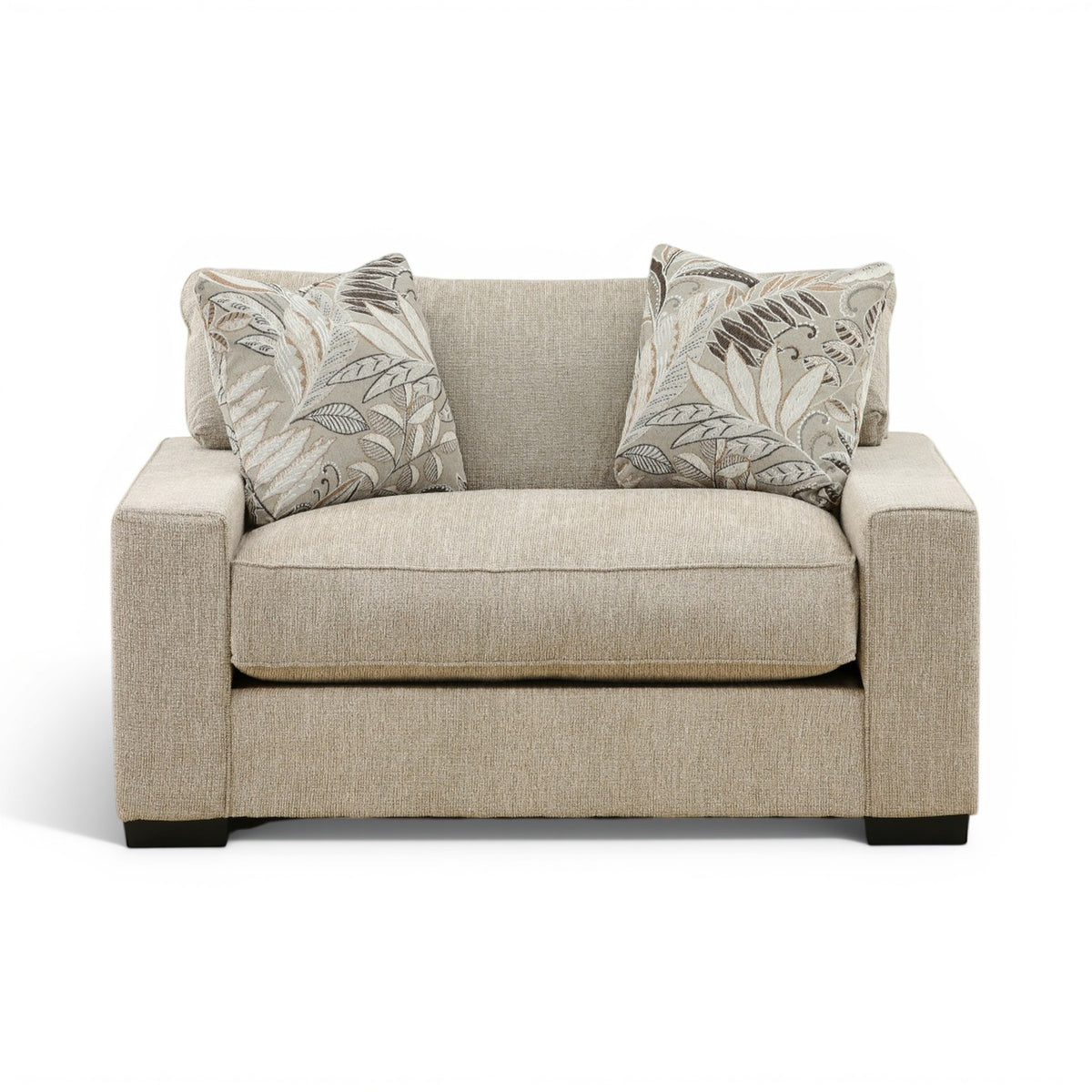Beige fabric loveseat chair with two leaf-pattern throw pillows