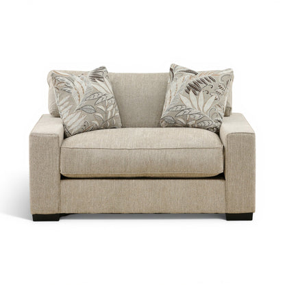 Beige fabric loveseat chair with two leaf-pattern throw pillows