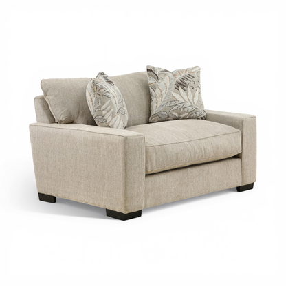 Beige fabric loveseat chair with two accent pillows and rolled arms