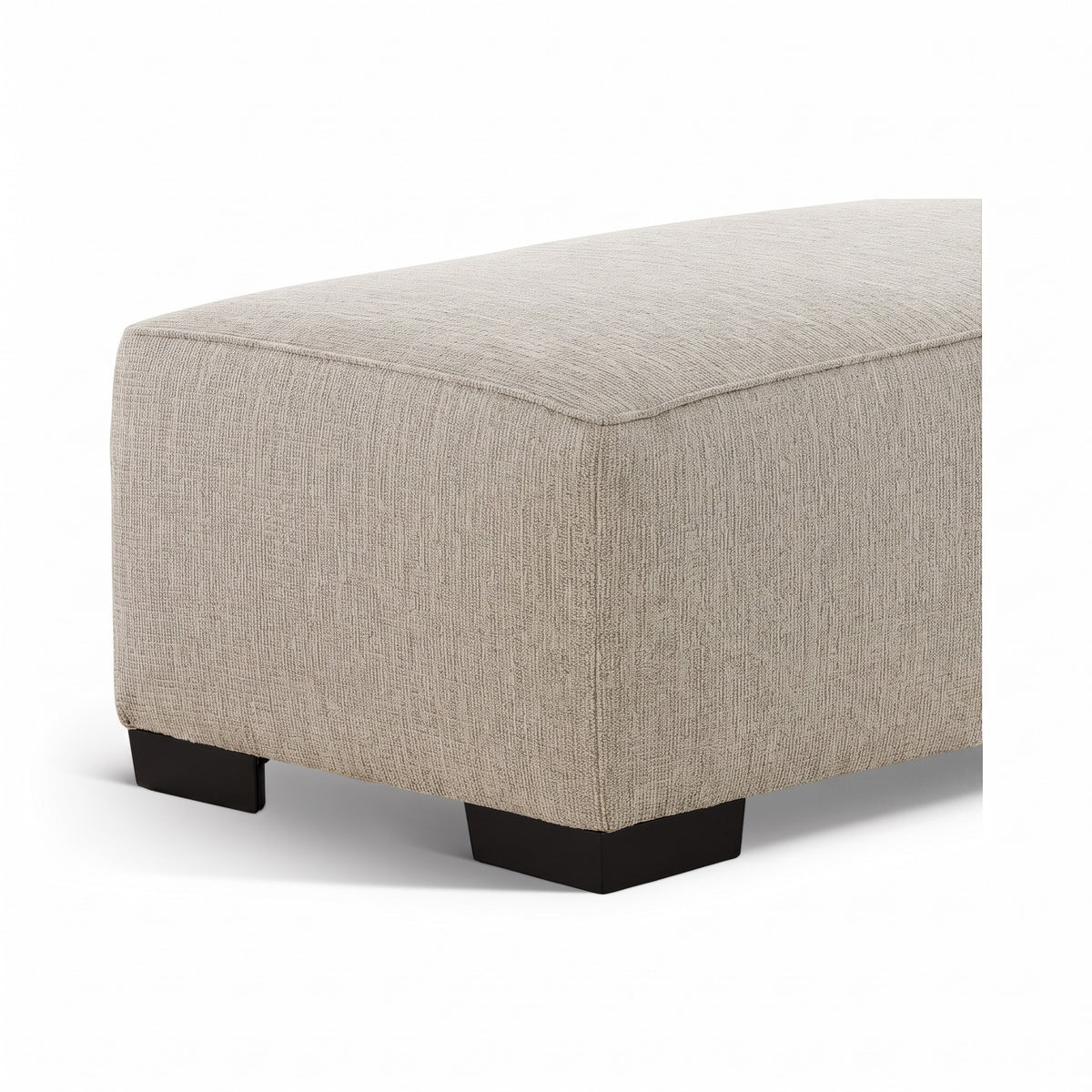 Light beige upholstered ottoman with rounded corner edges and black legs