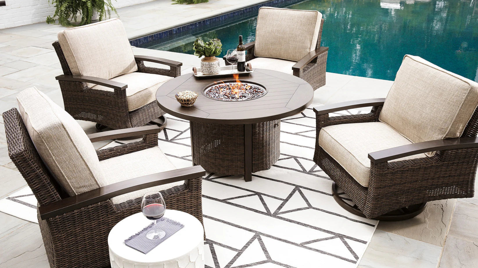 Outdoor patio set with chairs and a fire pit table by a pool.
