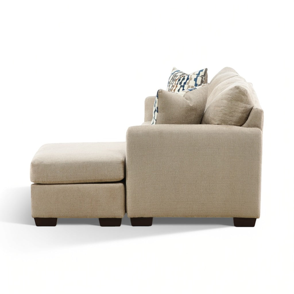 Parchment sofa chaise side view with chaise ottoman and patterned pillows; dark feet visible.