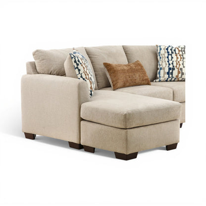 Parchment chaise sofa with wide armrest and patterned and tan throw pillows