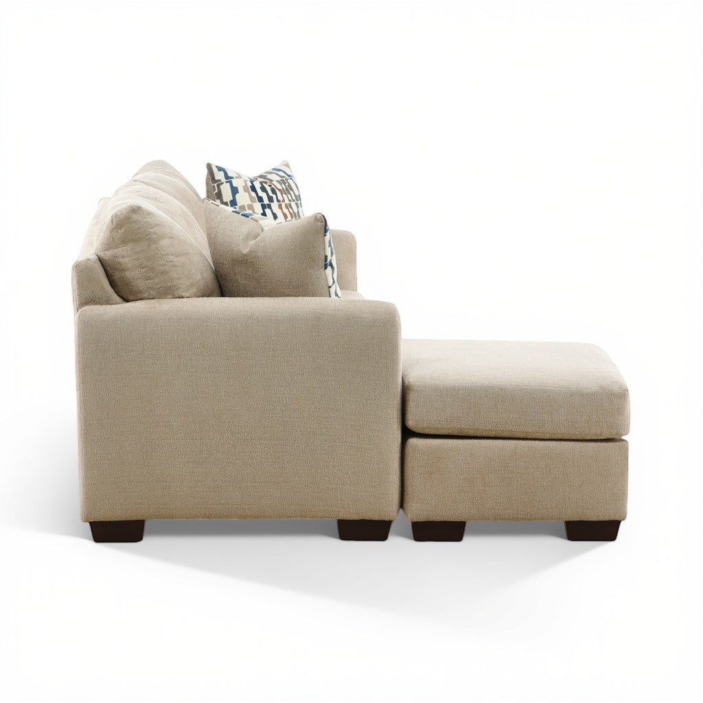 Parchment sofa chaise with chaise ottoman side view and layered back pillows; dark feet.