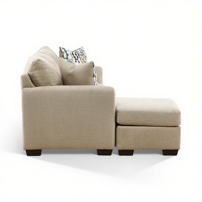 Parchment sofa chaise with chaise ottoman side view and layered back pillows; dark feet.