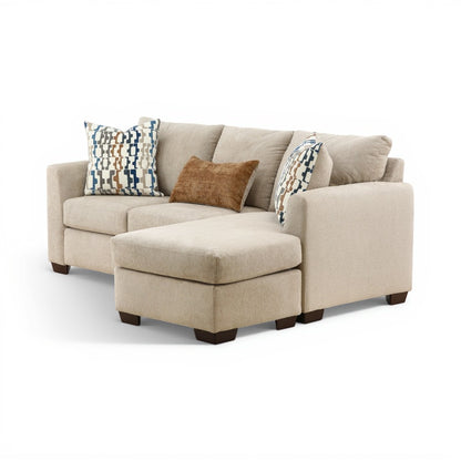 Parchment sofa chaise with chaise ottoman, brown accent cushion, and patterned pillows.