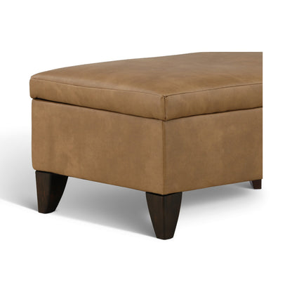 Brown faux-leather storage ottoman with cushioned top and dark wooden legs