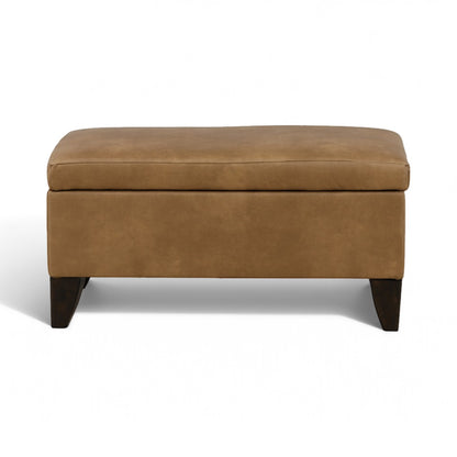 Tan storage ottoman with padded top and dark wooden legs, closed