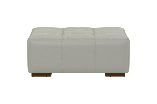 Pebble gray ottoman with horizontal stitching and tufted seat, brown base legs