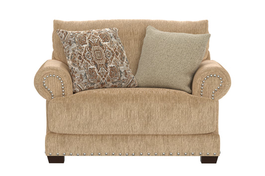 Sand upholstered chair with two cushions, patterned throw pillow, and nailhead trim