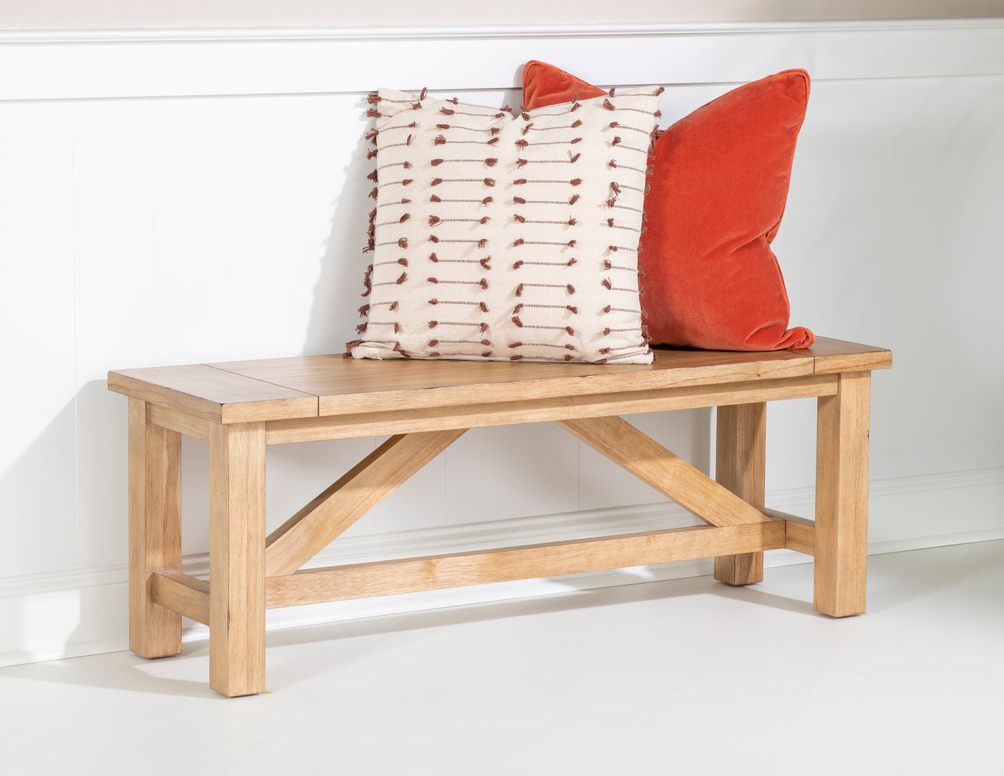Light wood bed bench with orange and cream decorative pillows