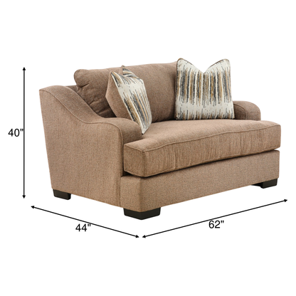 Upholstered lounge chair in tan fabric with two patterned throw pillows