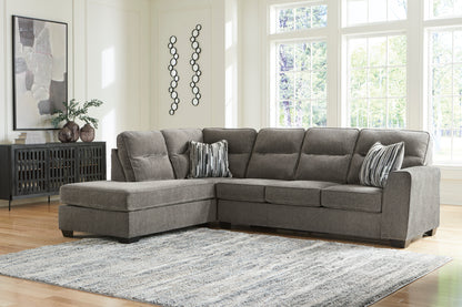 Left-facing graphite sectional with chaise and striped pillows in a living room.