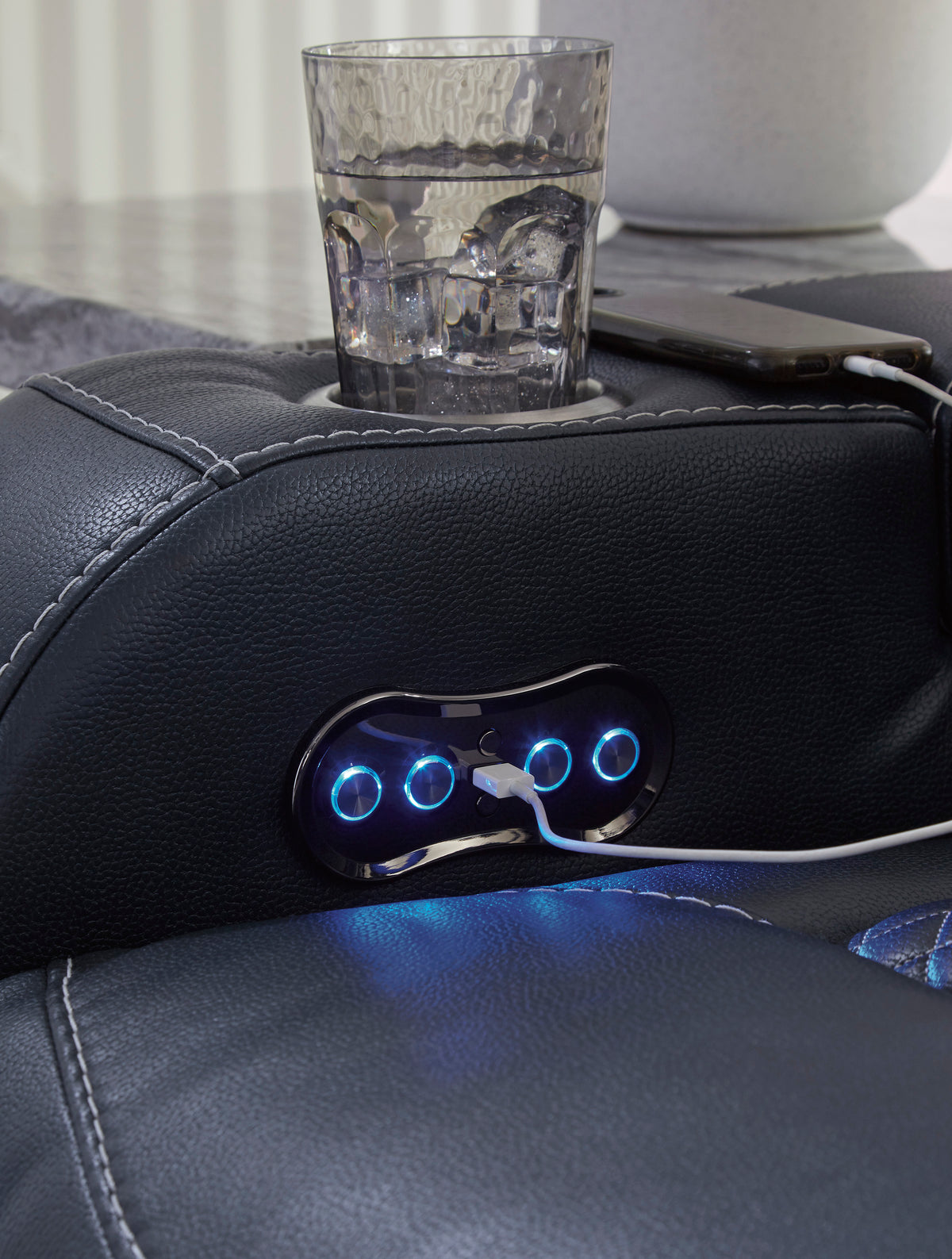 Black armrest console with two blue-lit buttons and cup holder
