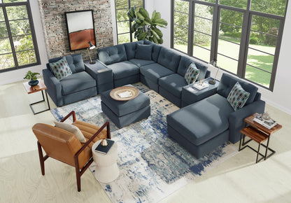 Blue-gray modular sectional sofa with patterned pillows and corner chaise ottoman seating