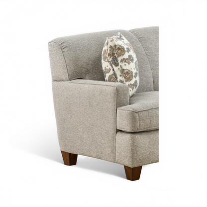 Beige upholstered armchair-style sofa with patterned throw pillow