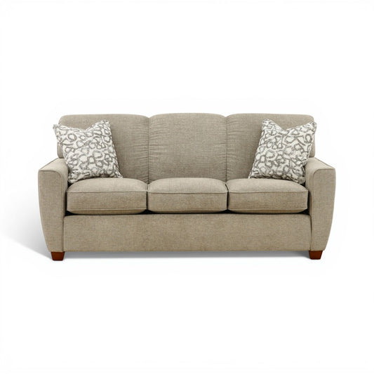 Beige fabric sofa with three seat cushions and patterned throw pillows, wooden feet
