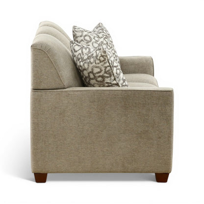 Beige upholstered sofa chair with high back and one patterned accent pillow, wooden feet