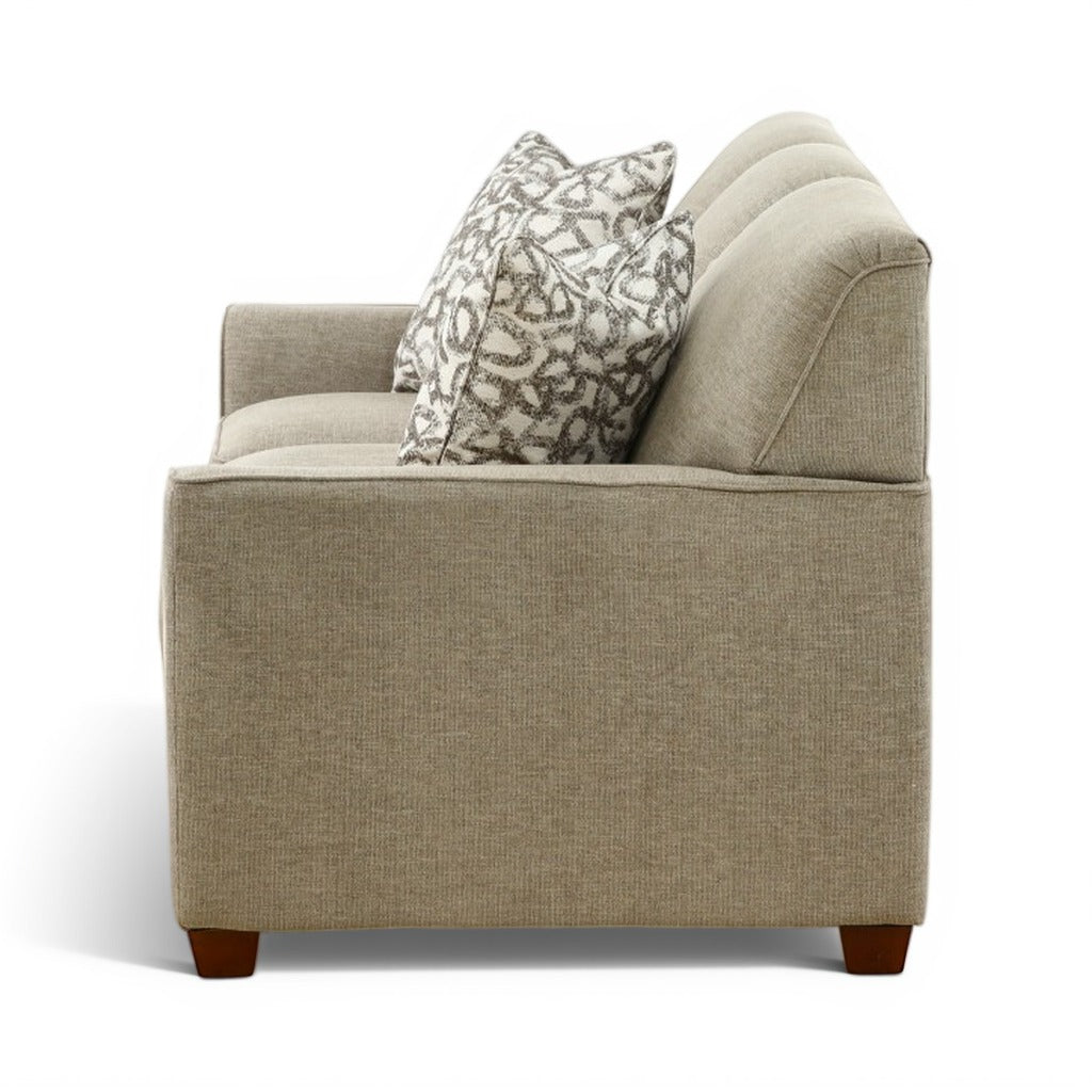 Beige upholstered sofa with patterned accent pillow and curved arm cushions, wooden feet