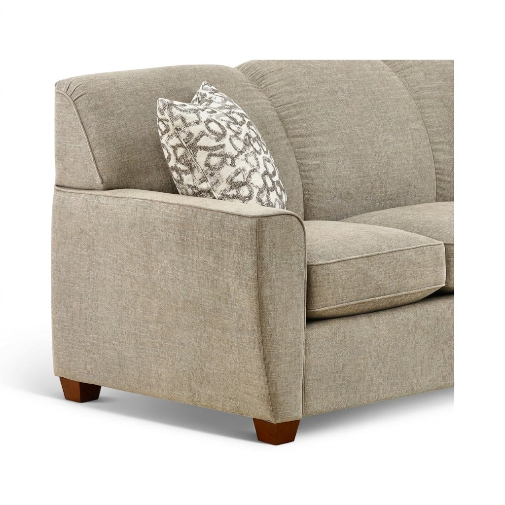 Beige upholstered sofa with rounded arms and patterned throw pillow, visible wooden base
