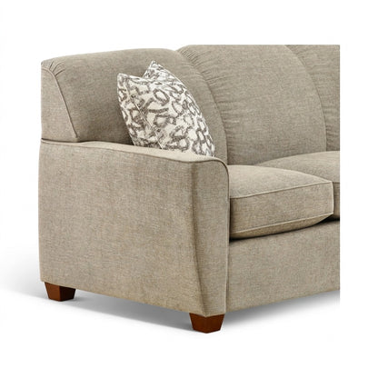 Beige upholstered sofa with rounded arms and patterned throw pillow, visible wooden base