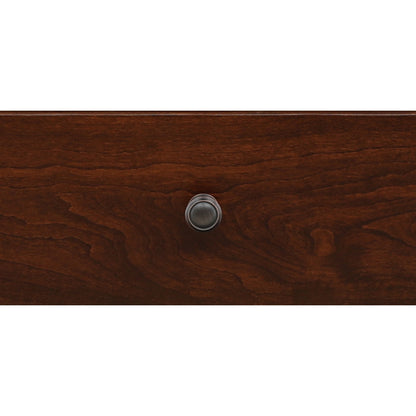 Close-up of round metal drawer pull on brown wood nightstand front