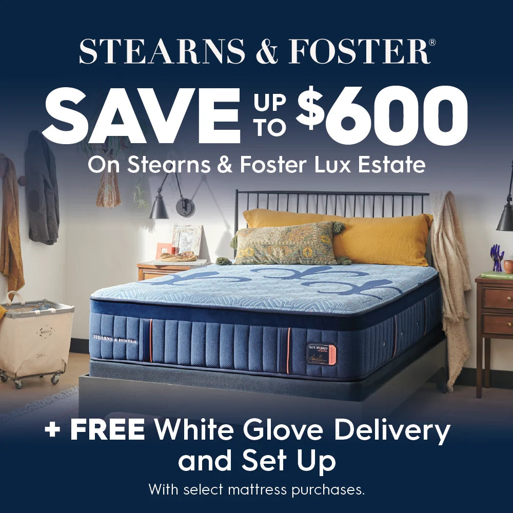 A mattress advertisement featuring a Stearns & Foster Lux Estate mattress in a styled bedroom setting. The ad includes large promotional text reading 'SAVE UP TO $600 On Stearns & Foster Lux Estate' and '+ FREE White Glove Delivery and Set Up With select mattress purchases.