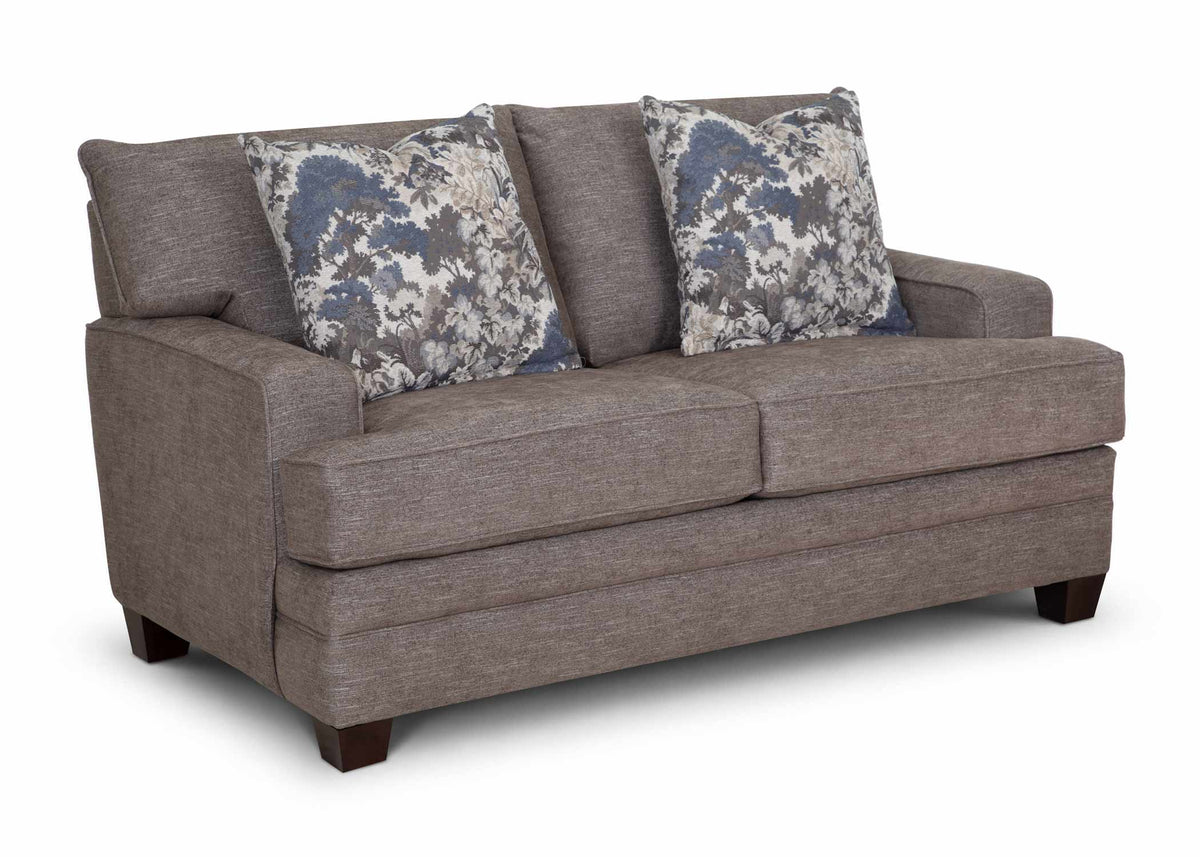 Gray upholstered loveseat with two seat cushions and two floral back throw pillows