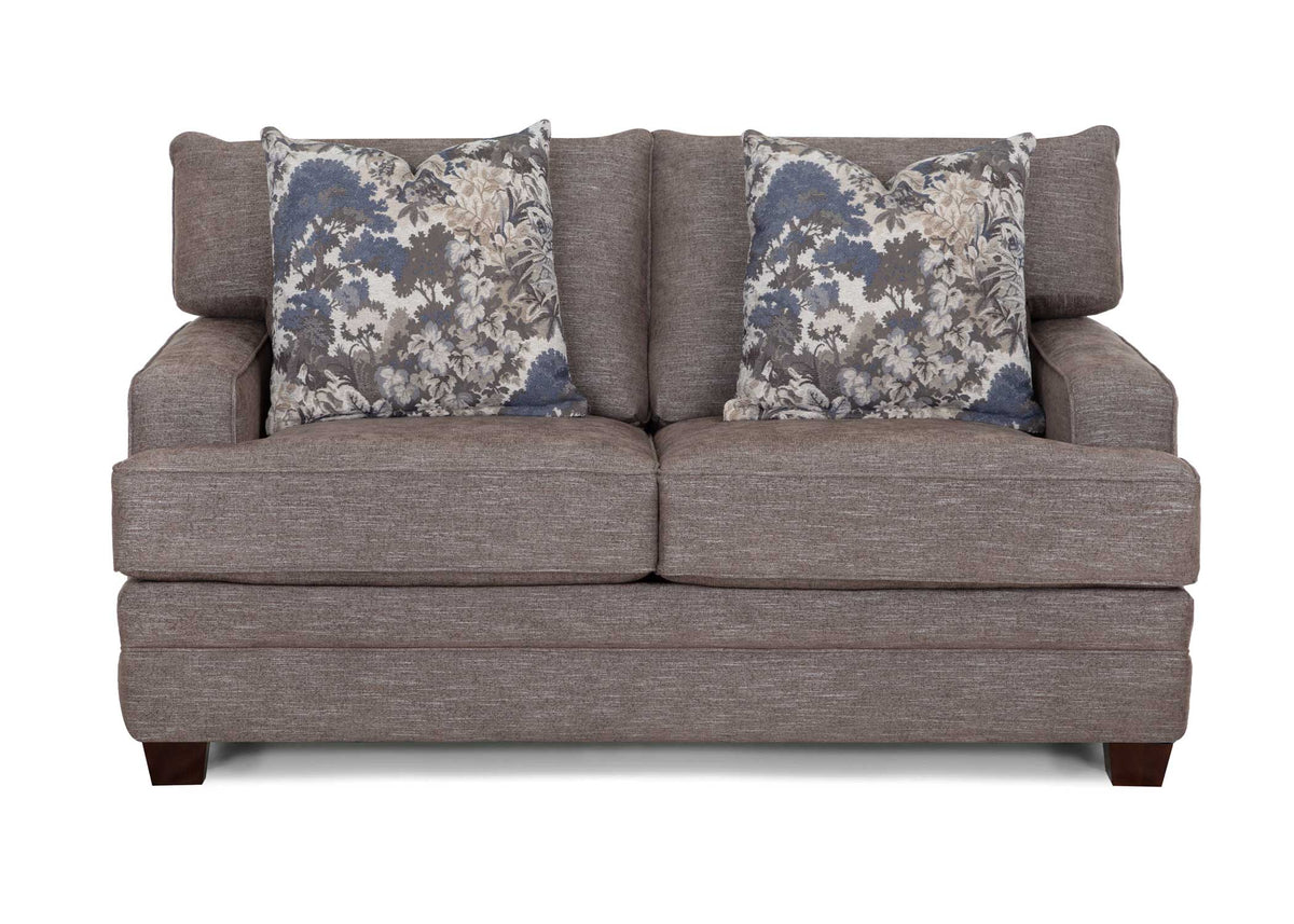 Gray loveseat sofa with rolled arms and two floral accent pillows