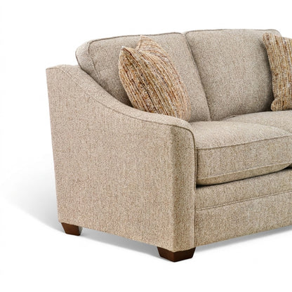 Beige fabric sofa corner view with rolled arm, three cushions, and two striped pillows.