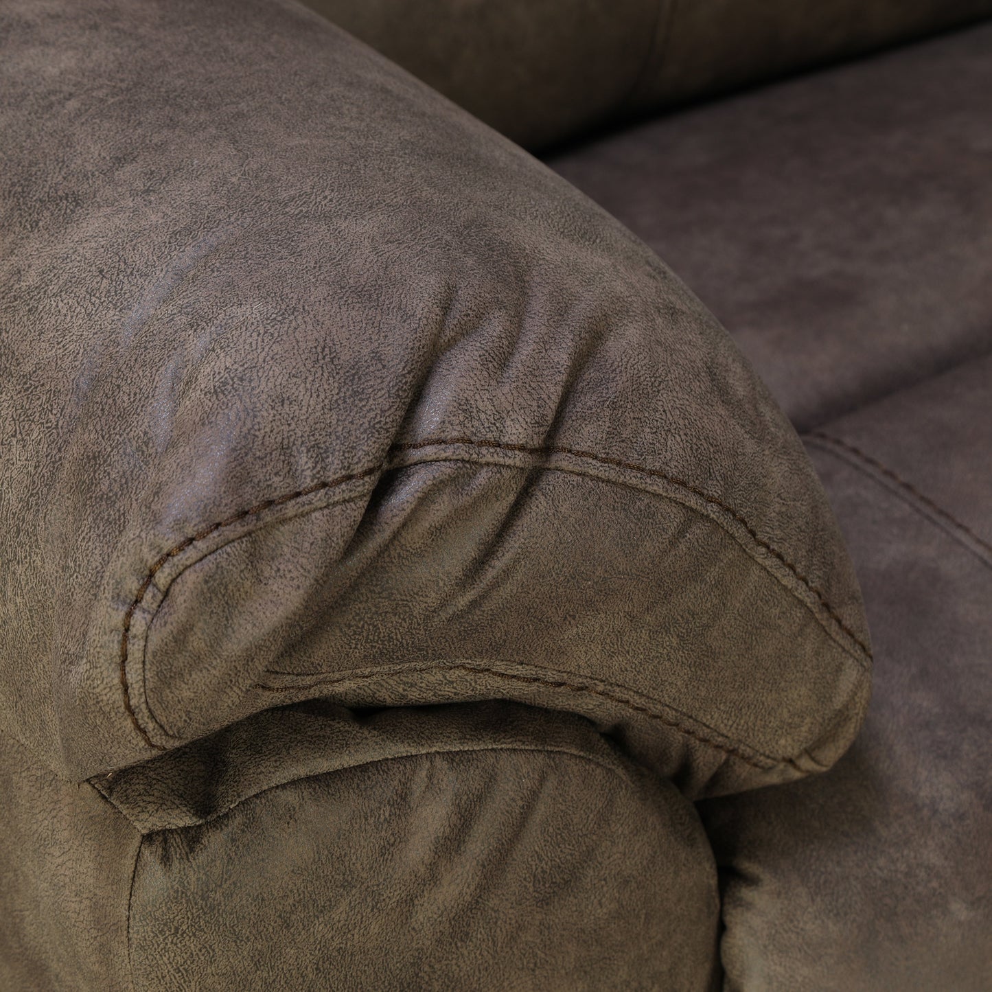Dark brown loveseat armrest and seat seam with curved stitching detail