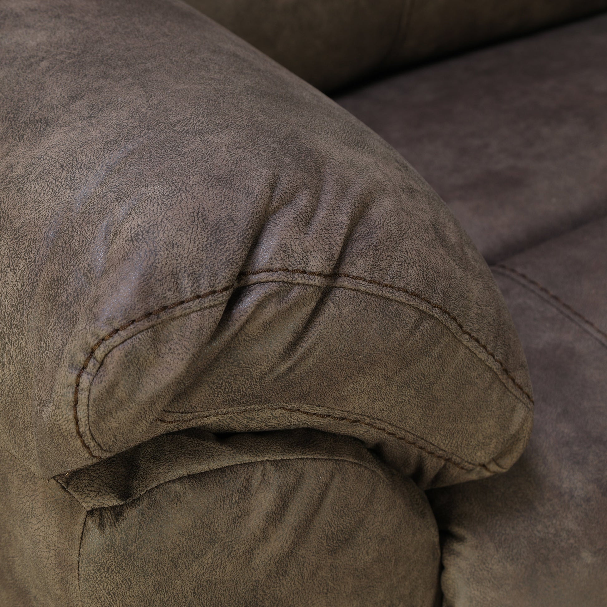 Dark brown loveseat armrest and seat seam with curved stitching detail